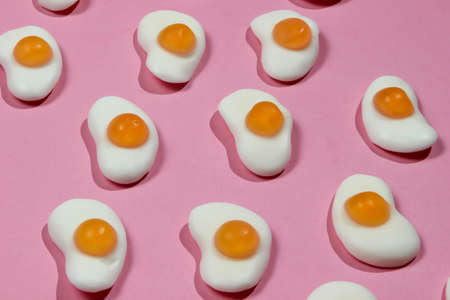 Pop art background. A lot of marmalade fried eggs on a pink pastel background. Minimalism food still...