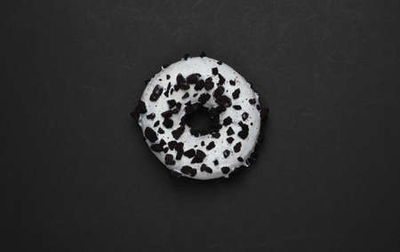 Glazed donut sprinkled with chocolate pieces on black background. Sweets cake, unhealthy food. Top viewの写真素材