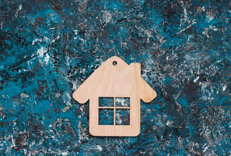 Wooden House figurine or keychain on blue concrete background. Top viewの写真素材