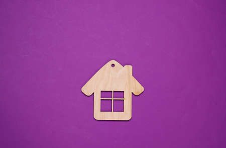 Wooden house figurine or keychain on purple background. Top viewの写真素材