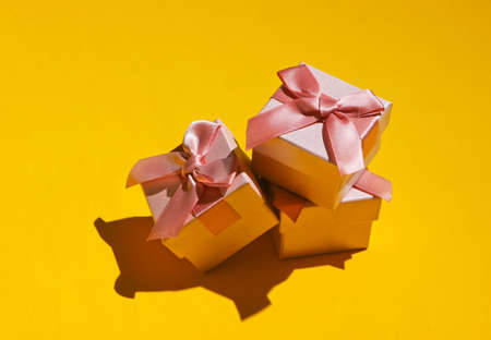 Pink gift box with bow on yellow background close-up. Holiday concept, birthday