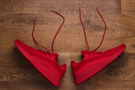 Red athletic shoes with untied laces on the floor. Top viewの写真素材