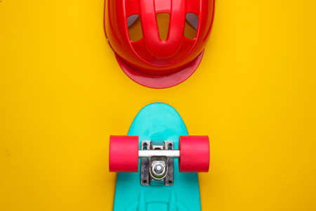 Cruiser board and safety helmet on a yellow background. Protective equipment for sports. Childhood. Top viewの写真素材