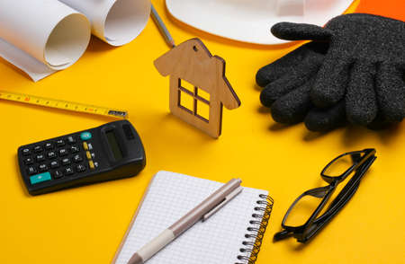 Roll drawings, engineering tools and stationery on yellow background, House building conceptの写真素材