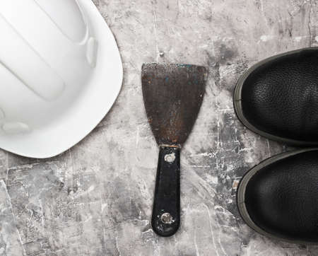 Trowel, leather boots, construction helmet on gray concrete background. Builder equipment. Top viewの写真素材
