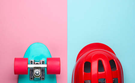 Cruiser board and safety helmet on pink blue pastel background. Protective equipment for sports. Childhood. Top viewの写真素材