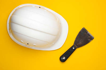 Trowel and construction helmet on a yellow background. Builder equipment. Top viewの写真素材