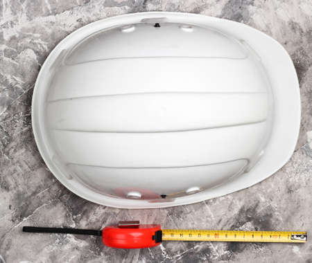 Construction helmet and measuring tape on gray concrete background. Top viewの写真素材