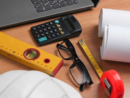 Roll drawings, architectural project plan, engineering tools and stationery, laptop on table, workspace.の写真素材