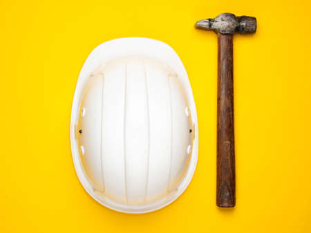 Hammer and construction helmet on a yellow background. Top viewの写真素材