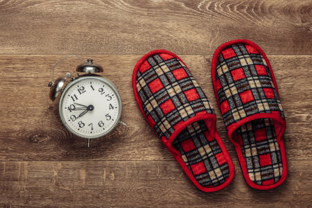 Healthy sleep. Indoor slippers and an alarm clock on the floor. Top viewの写真素材