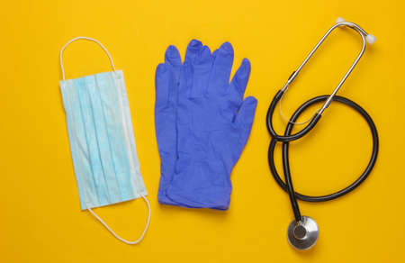 Epidemic. Medical gloves and mask, stethoscope on a yellow background. Top viewの写真素材