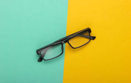 Classic eyeglasses on a yellow-blue background. Top view. Minimalismの写真素材