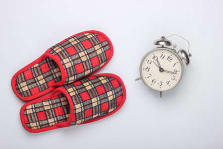 Checkered indoor slippers, alarm clock on a white background. Top viewの写真素材