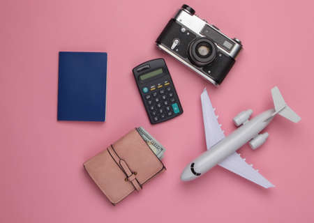Calculation of the cost of rest, air flight. Travel background. Traveler, tourist accessories, toy airplane, calculator on pink background. Top view.の写真素材