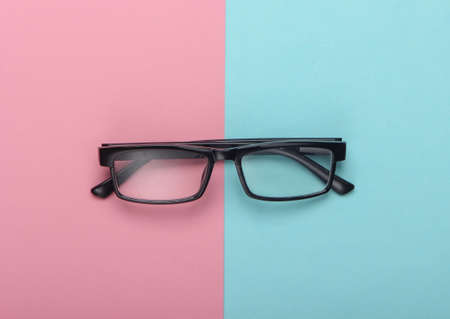 Classic eyeglasses on pink blue pastel background. Top view. Minimalismの写真素材