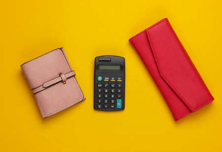 Calculator with leather wallets on yellow background. Family bujet, economical calculation, additional accounts of expenses. Top viewの写真素材