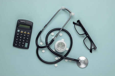 Doctoral supplies and tools, calculator on blue background. Economic calculation of the effectiveness of healthcare and medicine. Doctor workspaceの写真素材