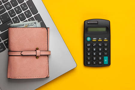 Economic calculation, profit analysis, family budget concept. Laptop, wallet, calculator on a yellow background. Workspace. Top viewの写真素材