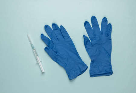 Vaccinations. Doctor gloves with syringe on blue background. Top viewの写真素材