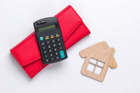 Calculation of rental housing, family budget, economic analysis. Calculator, wallet with house figure on white background. Top viewの写真素材