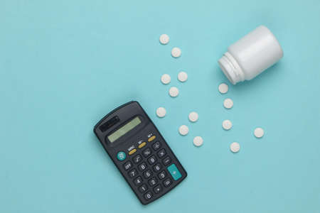 Economic calculation of the cost of treatment, analysis of the cost of medicines. Bottle of pills, calculator on blue background. Top viewの写真素材