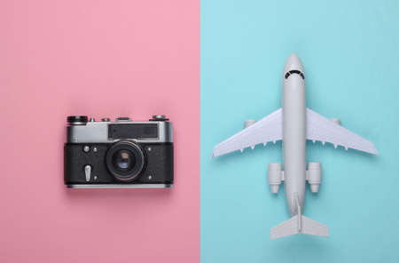 Flat lay travel composition on pink blue pastel background. Plane figurine and film camera....