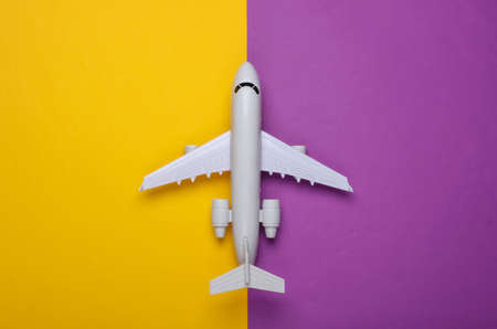 Toy model of plane on a purple yellow background. The concept of tourism, air travel, minimalism. Top viewの写真素材