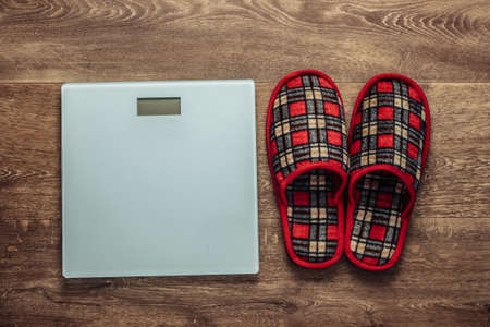 Indoor slippers and scales on floor. The concept of losing weight. Top viewの写真素材