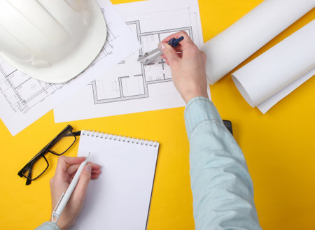 Engineering workspace. Female hands make calculations and measurements on a yellow background. Top viewの写真素材