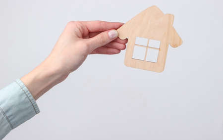 Wooden figurine of a house in female hand on a white backgroundの写真素材