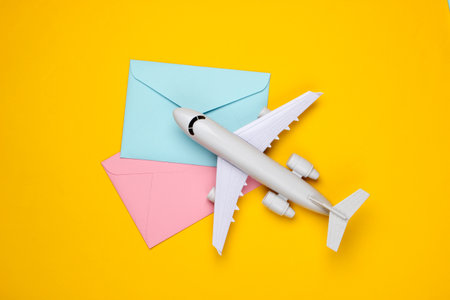 Air mail, air delivery. Flat lay composition with airplane figure and envelopes of letters on yellow...