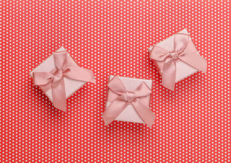 Gift boxes with bows on a red polka dot background. Top view