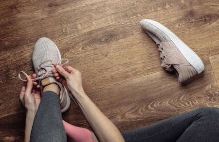 Fitness, sport concept. Woman tying shoelaces of sports shoes for running while sitting on the...