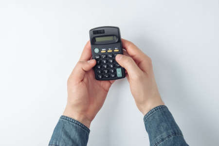 Male hands count on a calculator on white backgroundの写真素材