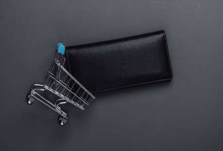 Shopping trolley with wallet on a black background. Top view. Minimalism shopping concept. Flat layの写真素材