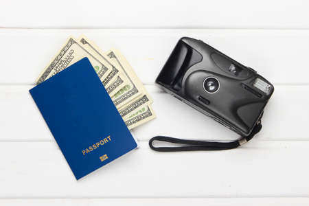 Passport with dollar bills and a camera on white wooden background. Flat lay travel composition. Top viewの写真素材