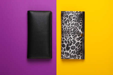 Two stylish wallets on purple yellow background. Fashion minimalism. Top viewの写真素材
