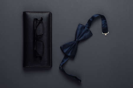 Wallet with glasses and a bow-tie on a black background. Top viewの写真素材