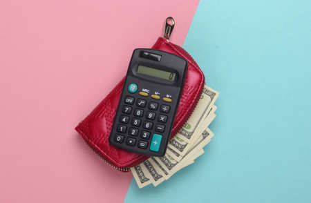 Red purse with hundred dollar bills and a calculator on a blue-pink pastel background. Counting the cost of purchases. Top viewの写真素材