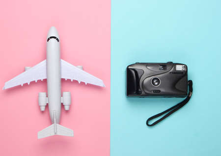 Flat lay design of travel concept with plane, camera. Pink blue pastel background. Minimalism. Top...