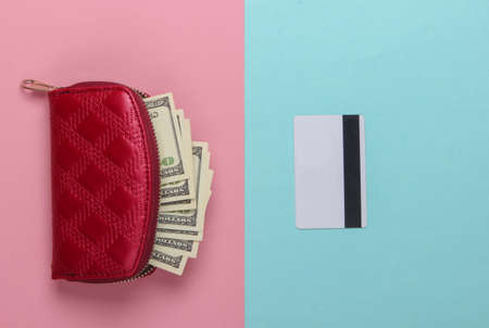 Red purse with hundred dollar bills and a bank card on a blue-pink pastel background. Top viewの写真素材