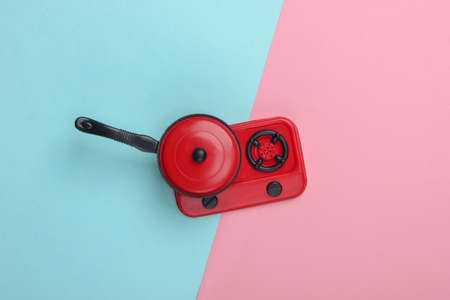 Toy plastic stove with pan on pink blue pastel  background. Kid's Kitchen. Top view, minimalismの写真素材