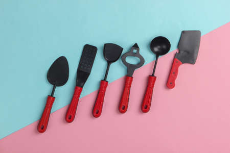 Toy kitchen tools on a pink-blue pastel background. Top view