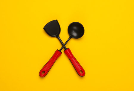 Toy kitchen tools on yellow background. Kitchen spatula, ladle. Top viewの写真素材