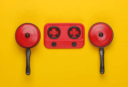 Toy plastic stove with pans on yellow background. Kid's Kitchen. Top view, minimalismの写真素材