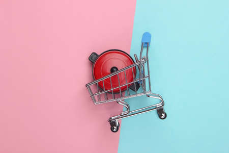 Miniature shopping trolley with pan on blue-pink pastel background. Top viewの写真素材