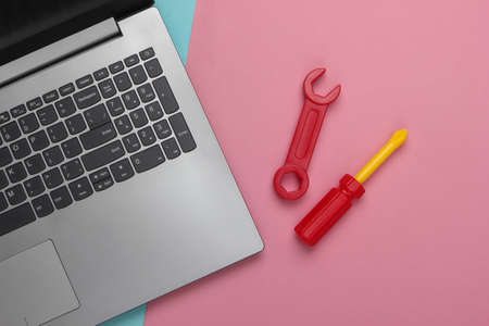Flat lay composition. Repair concept. Laptop with toy work tools on pink blue pastel background. Top viewの写真素材