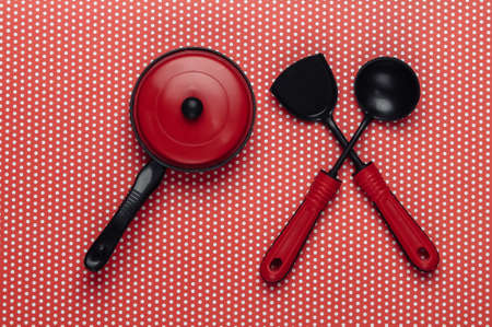 Toy kitchen tools and pan on a polka dot tablecloth. Top view