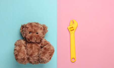 Teddy bear and toy wrench on a blue pink pastel background. Repair concept. Top viewの写真素材